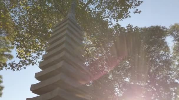 Cinematic panning of sunbeam over stone Japanese pagoda - Záběry, video
