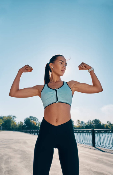 Strong and confident beautiful woman flexing her muscles. Sport concept - Φωτογραφία, εικόνα
