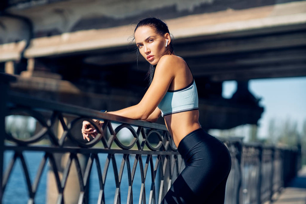 Beautiful confident woman in sportswear posing outdoors. Beauty and sport concept - Foto, afbeelding