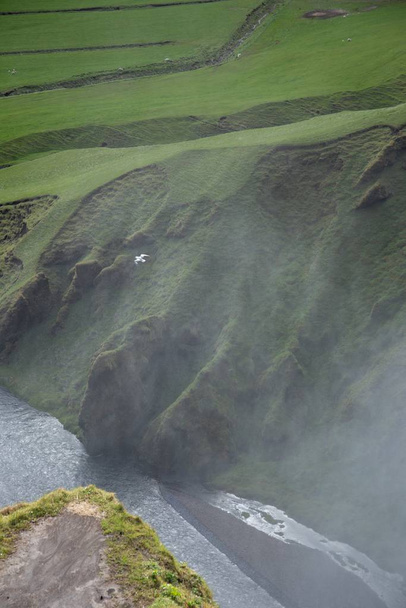 Vertical aerial shot of a river going through the grass covered hills captured in Iceland - Foto, Bild