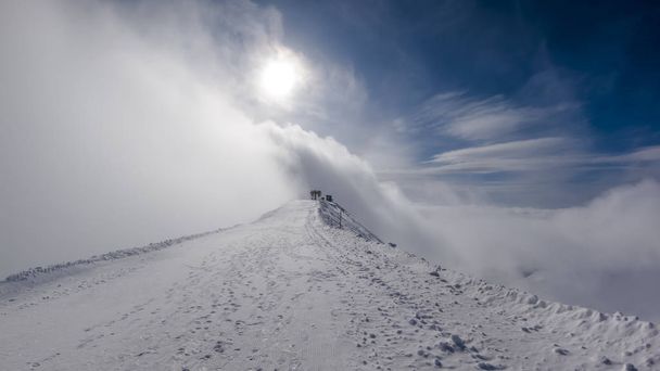 die Straße mit den Spuren von Stiefeln zum Lift während eines Schneesturms auf dem Gipfel des Berges. - Foto, Bild