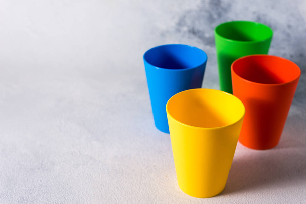 tazas de plástico de color de grupo sobre fondo de piedra gris residuos de plástico
 - Foto, imagen