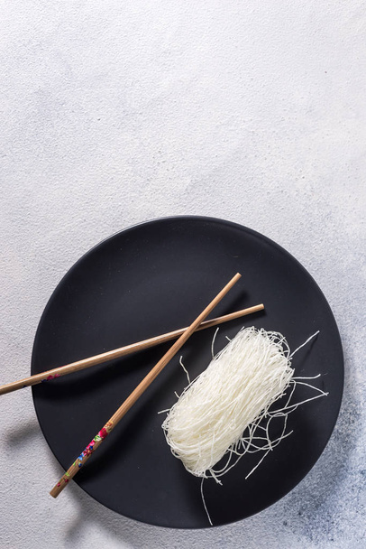 Chinese glass noodles with chopsticks on a dark plate with place for text - Foto, Imagem