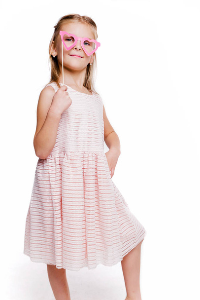 Bella ragazza in un abito rosa e occhiali in cartone sotto forma di cuori
 - Foto, immagini