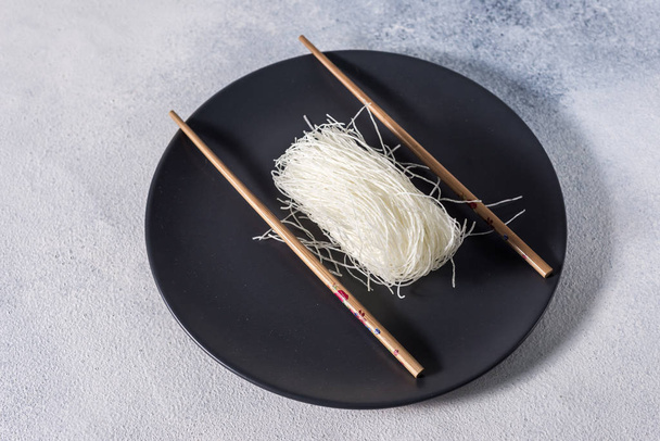 Chinese glass noodles with chopsticks on a dark plate with place for text - Photo, Image