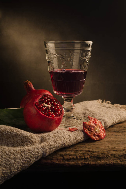 Red pomegranate with a tall vintage  wineglass - Фото, изображение