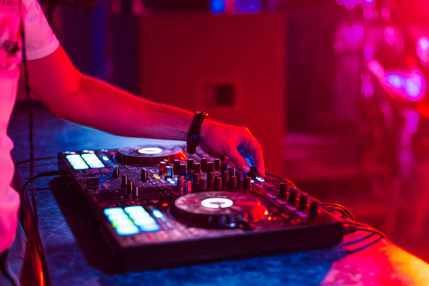 hands of a DJ mixing music on a professional controller in a booth - Fotoğraf, Görsel