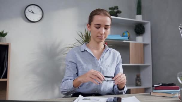 Attractive joyful young woman putting on glasses and opening the laptop to make online shopping using her bank card - Séquence, vidéo
