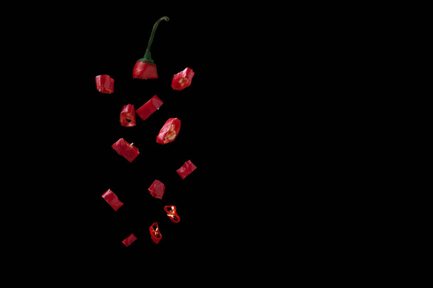 pimiento rojo picante cortado en trozos sobre un fondo negro
 - Foto, imagen