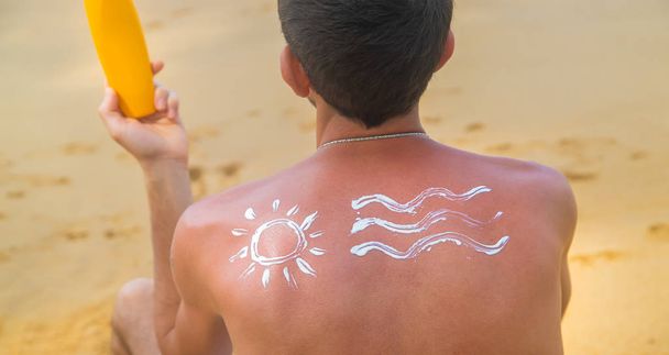 Egy férfi a parton, naptejjel a hátán. Szelektív fókusz. - Fotó, kép