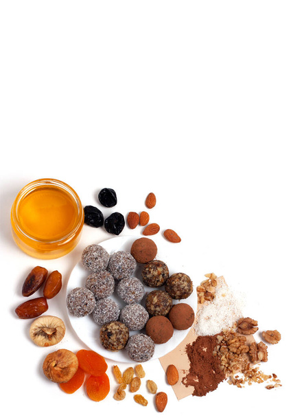 Dried fruits. On the table are colorful useful homemade sweets with nuts. Copy space. White background. Healthy diet. Colorful healthy homemade candies with nuts, dried fruits and spices - Фото, зображення