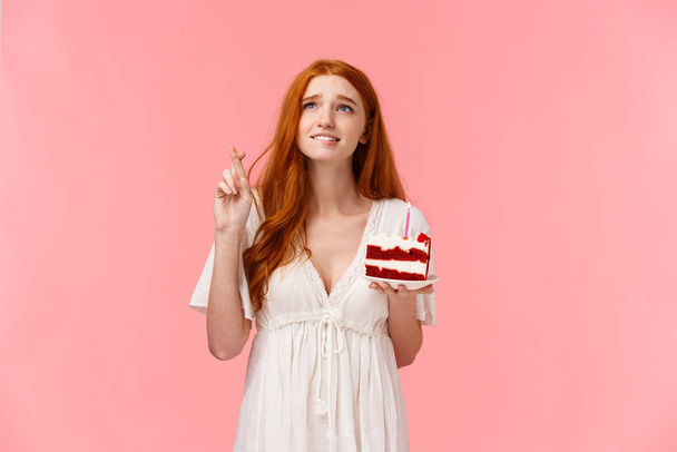 Waist-up portrait intense and wishful cute redhead b-day girl want dream come true badly, frowning intense looking up sky, biting lip and cross fingers good luck, blow candle on birthday cake - Photo, Image