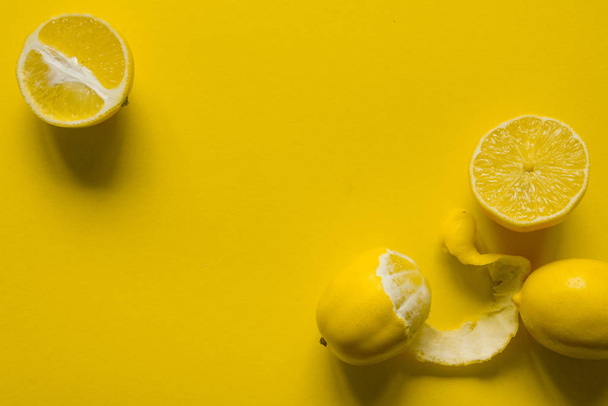 Верхний вид цельных и нарезанных спелых лимонов на желтую поверхность, концепция здоровья и витаминов
 - Фото, изображение