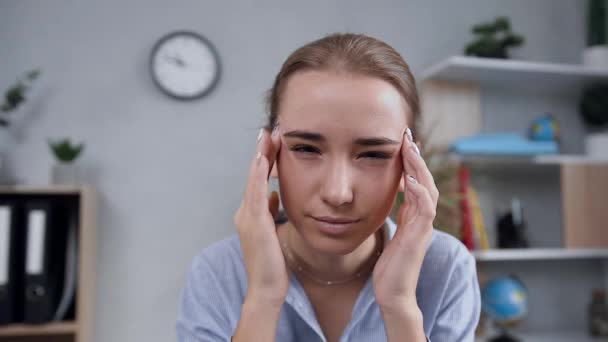 Menina loira atraente infeliz massageando os templos para aliviar a dor de cabeça durante seu trabalho no computador no armário moderno
 - Filmagem, Vídeo