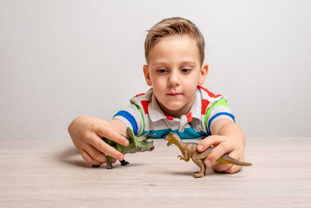 Junge hält Dinosaurier-Spielzeug in der Hand. Konzept der Entwicklung von Aufmerksamkeit bei Kindern durch Spiel - Foto, Bild
