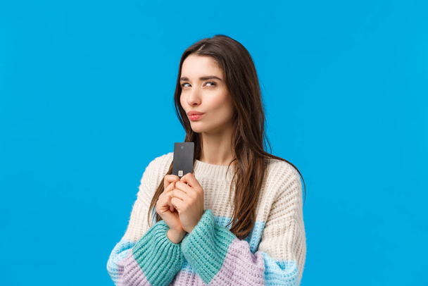 Thoughtful and sly attractive girl stole dads credit card and thinking how waste money, imaging something good, pondering what buy during winter shopping discount season, squinting mysterious - Photo, Image