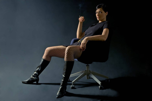 young woman in a black suit sitting on a chair - Photo, Image