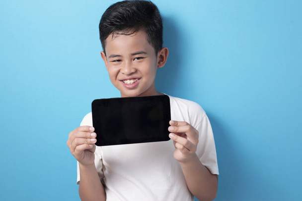 Asian boy shows his tablet screen, tablet smart phone mock up - Foto, imagen