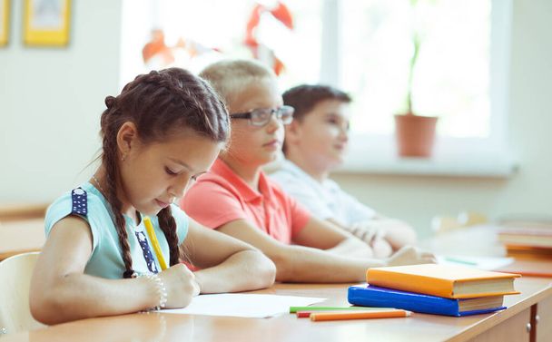 Cute schoolchildren study and answer questions in classroom duri - Фото, изображение