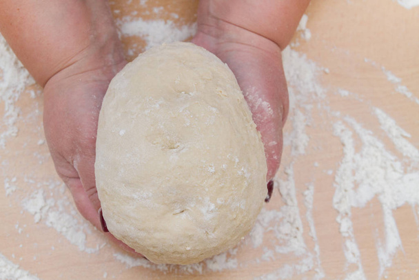 Kneading dough with flour on a wooden table at home - Φωτογραφία, εικόνα