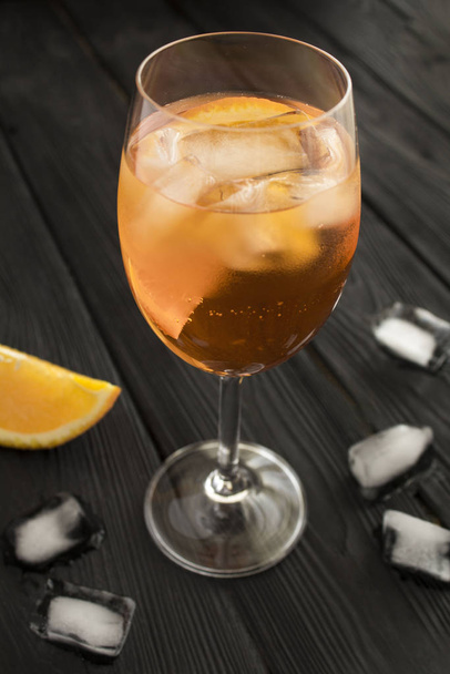 Aperol spritz cocktail in wine glass on the black wooden background. Location vertical. Closeup. - Foto, immagini