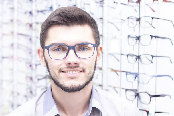 healthcare, people, vision and vision concept. men smiling trying on glasses in the store. - Foto, Imagen