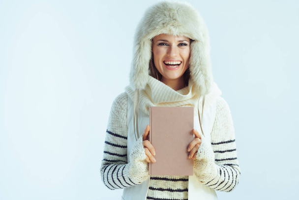 smiling woman with book against winter light blue background - Foto, afbeelding