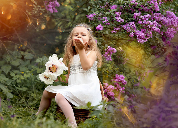 Κοριτσάκι με λευκό φόρεμα περπατάει στον ανοιξιάτικο βοτανικό κήπο - Φωτογραφία, εικόνα
