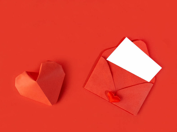 Κόκκινο χάρτινο φάκελο με σημείωμα για την Ημέρα του Αγίου Βαλεντίνου σε λευκό φόντο με καρδιές - Φωτογραφία, εικόνα
