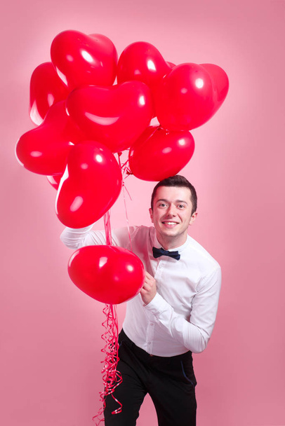 young man with heart shape air balloons on pink background. man on Valentines Day. - Fotografie, Obrázek