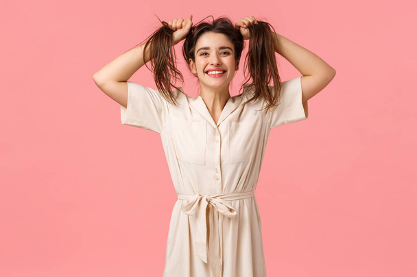 Joy, party and happiness concept. Silly funny girl having fun fooling around, pulling hair sideways making it messy, smiling cheerfull, enjoy perfect day feeling amused and upbeat, pink background - Photo, Image