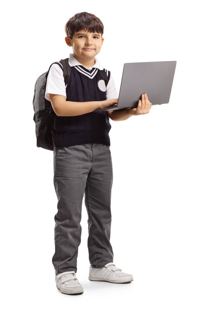 Schoolboy in a uniform holding a laptop computer - Foto, afbeelding