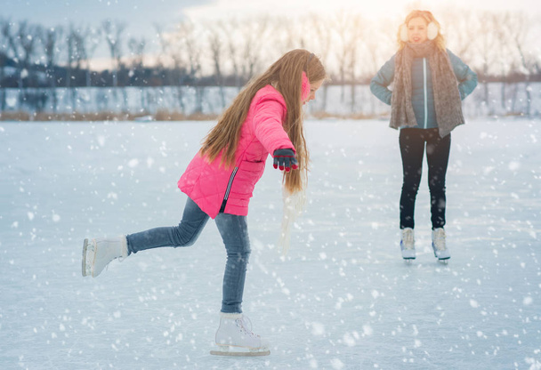 junge Familie genießt einen Tag auf der Eisfläche in einem verschneiten Park - Foto, Bild