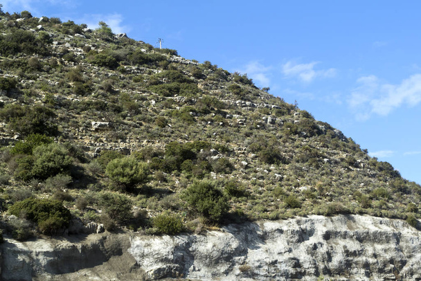 Berghang mit weißen Felsen, grünen Sträuchern und blauem Himmel mit weißen Wolken - Foto, Bild