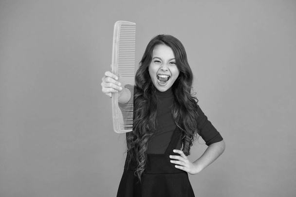 Get rid of annoying tangles. Large comb. Girl long hair hold enormous comb close up. Hairdresser salon. Combing hair. Cheerful smiling little kid with giant comb. Styling tips. Comb for tangled hair - Foto, Imagem