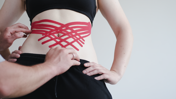 Persona con cinta de cinesiología roja en el estómago en clínica privada
 - Metraje, vídeo