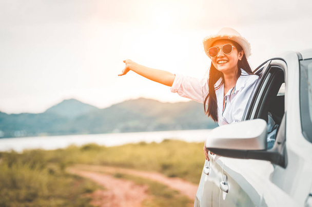 glückliche Frau winkt Hand vor offenem Fenster Auto mit Wiese und  - Foto, Bild