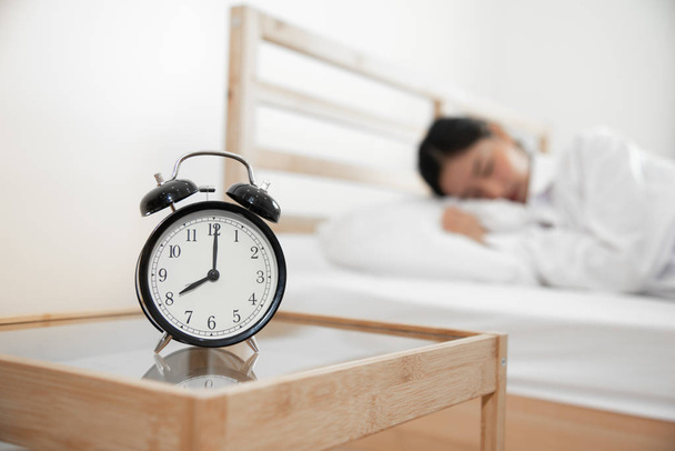 Closeup alarm clock with sleeping woman in bed room. Lazy time i - Fotoğraf, Görsel