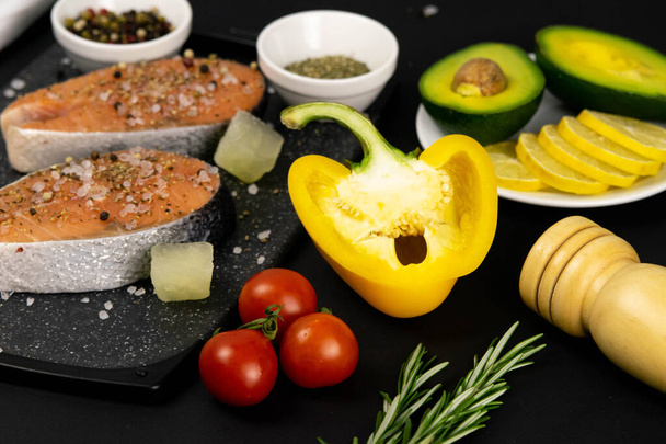 Een set van gezonde uitgebalanceerde superfood, verse zalm, groenten, ei, granen en noten op een zwarte achtergrond. - Foto, afbeelding