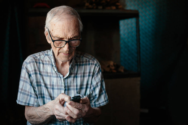Elderly man using small cell phone  at home - Fotoğraf, Görsel