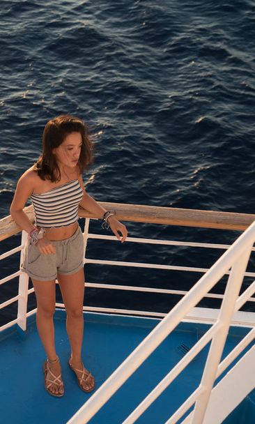 Asiático adolescente de pie en la cubierta azul de ferry barco en el camino a Les
 - Foto, imagen