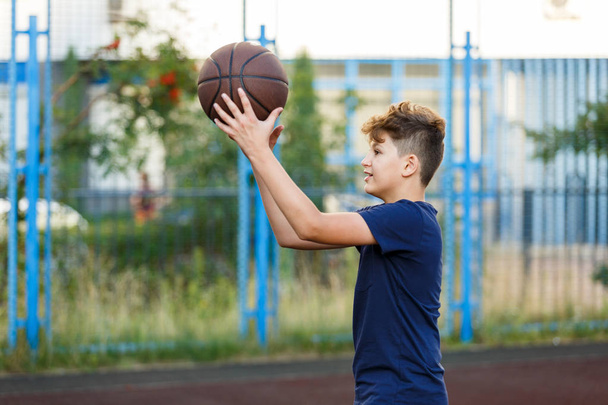 poika pelaa koripalloa kentällä - Valokuva, kuva
