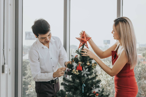 Young Asian couple decorating christmas tree together at home, h - Zdjęcie, obraz