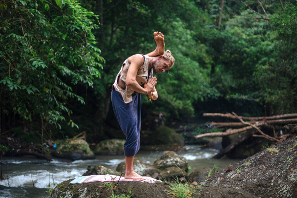 Yoga uygulaması ve doğada meditasyon. Nehir yakınlarında pratik yapan adam - Fotoğraf, Görsel