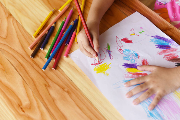 Девушка рисует на бумажном листе с цветными карандашами на деревянном t
 - Фото, изображение