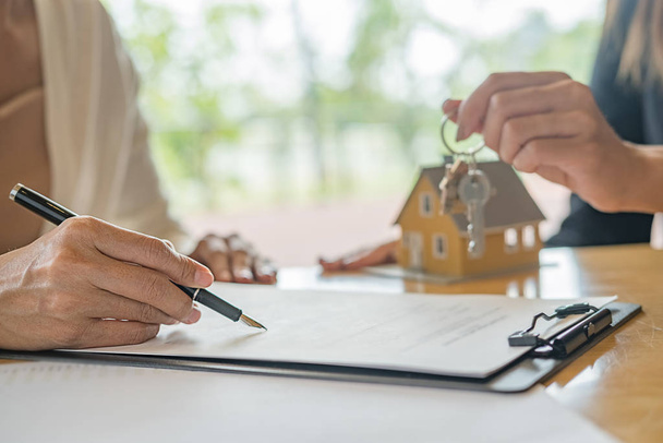 Hausmodell mit Makler und Kunde, die über einen Kaufvertrag, eine Versicherung oder ein Darlehen für Immobilien oder Immobilien diskutieren. - Foto, Bild