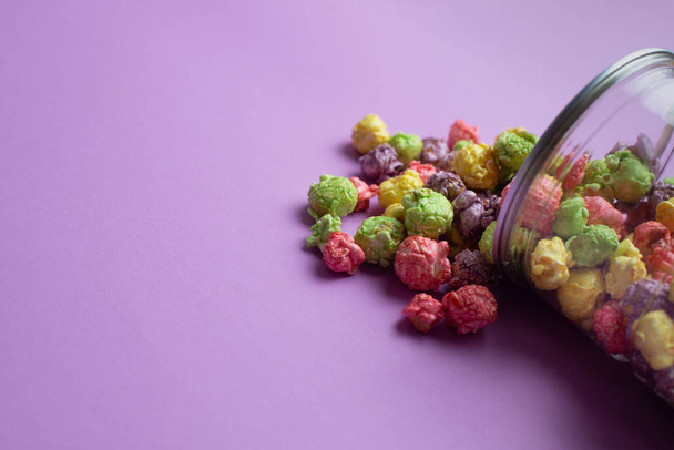 Різнокольорові фрукти зі смаком попкорну в скляних чашках на рожевому фоні. цукерки покриті попкорном
. - Фото, зображення