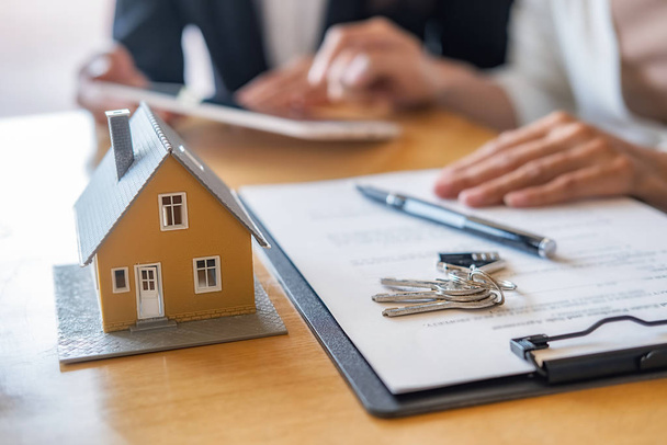 Modello di casa con agente e cliente discutere per il contratto di acquistare, ottenere l'assicurazione o prestito immobiliare o immobiliare. - Foto, immagini