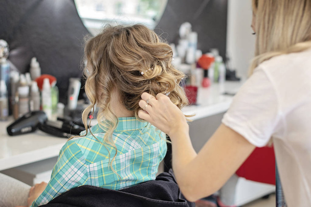 Beautiful curly special occasion hairstyle. Hairdresser makes hairstyle - Fotografie, Obrázek