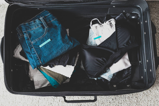 luggage with two pile of clothes and Packing Everything vs Pack  - 写真・画像